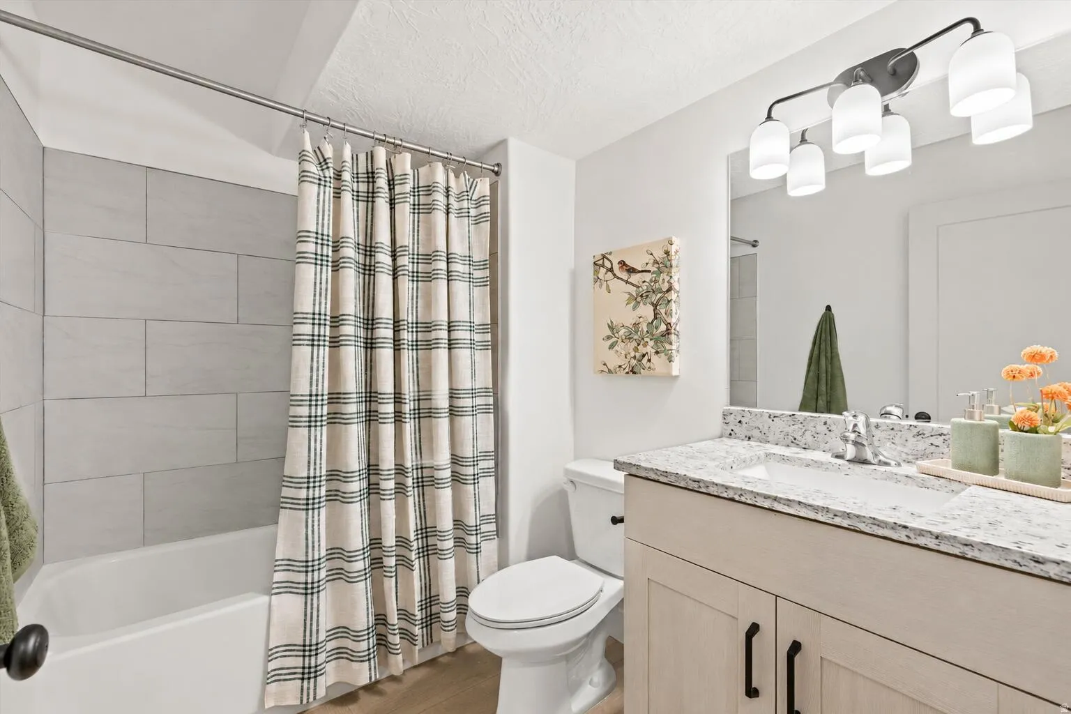 Bathroom featuring a white bathtub, light gray tile surround, and wood-finish flooring