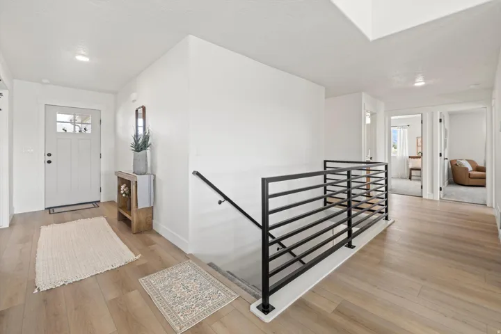 Bright entryway featuring a white paneled door with glass inserts, wood-finish flooring, and recessed lighting
