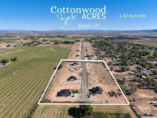 Aerial perspective featuring multiple developed lots with residential structures and surrounding undeveloped land