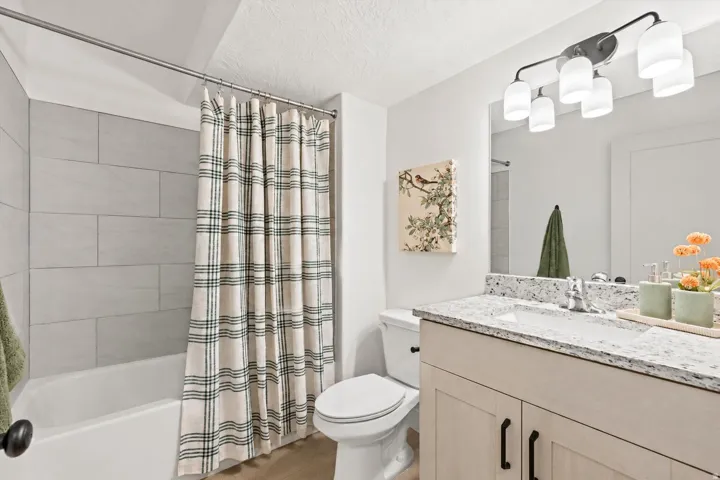 Bathroom featuring a white bathtub, light gray tile surround, and wood-finish flooring