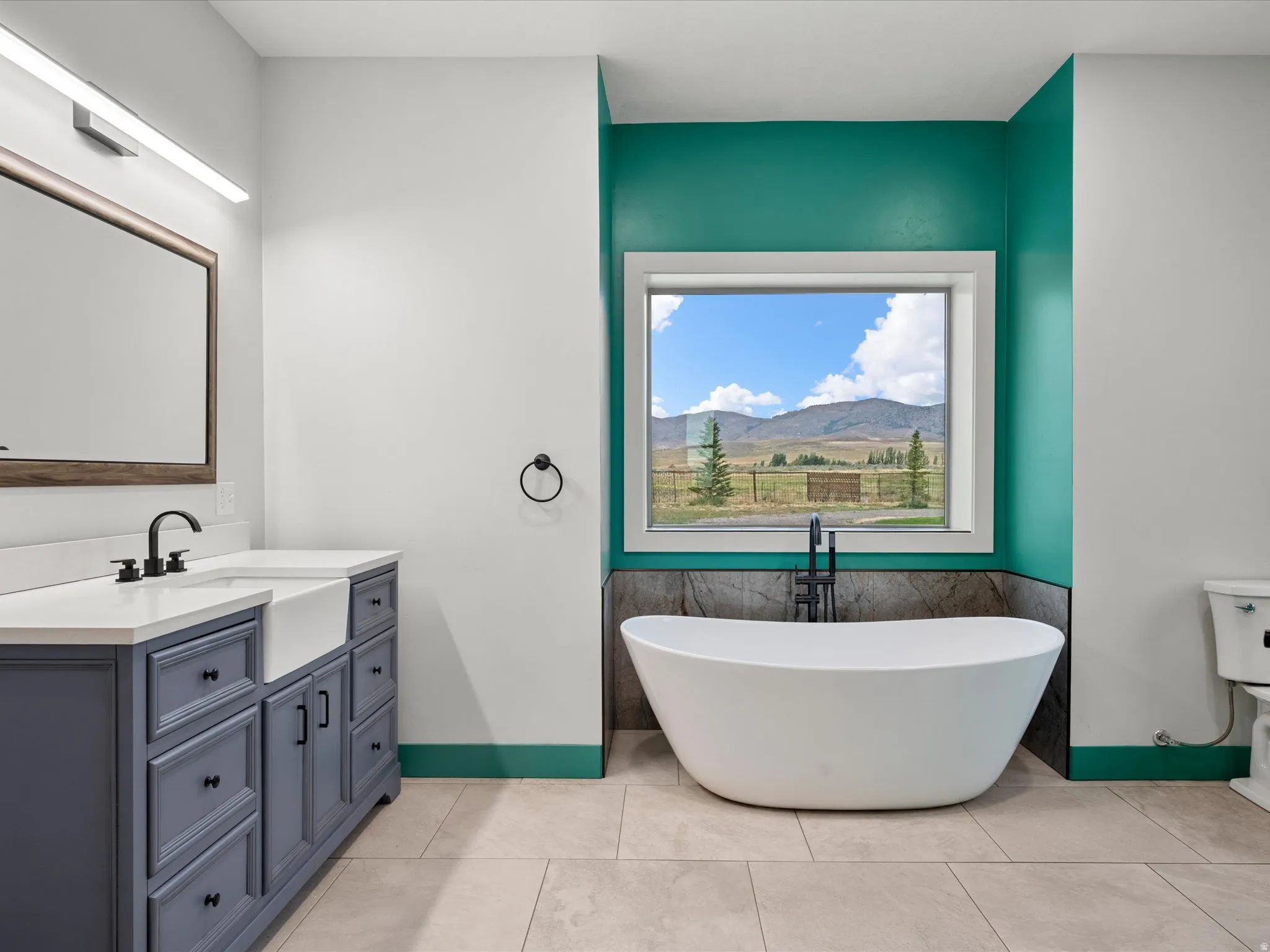 Freestanding soaking tub with floor-mounted faucet, set against a window with mountain scenery