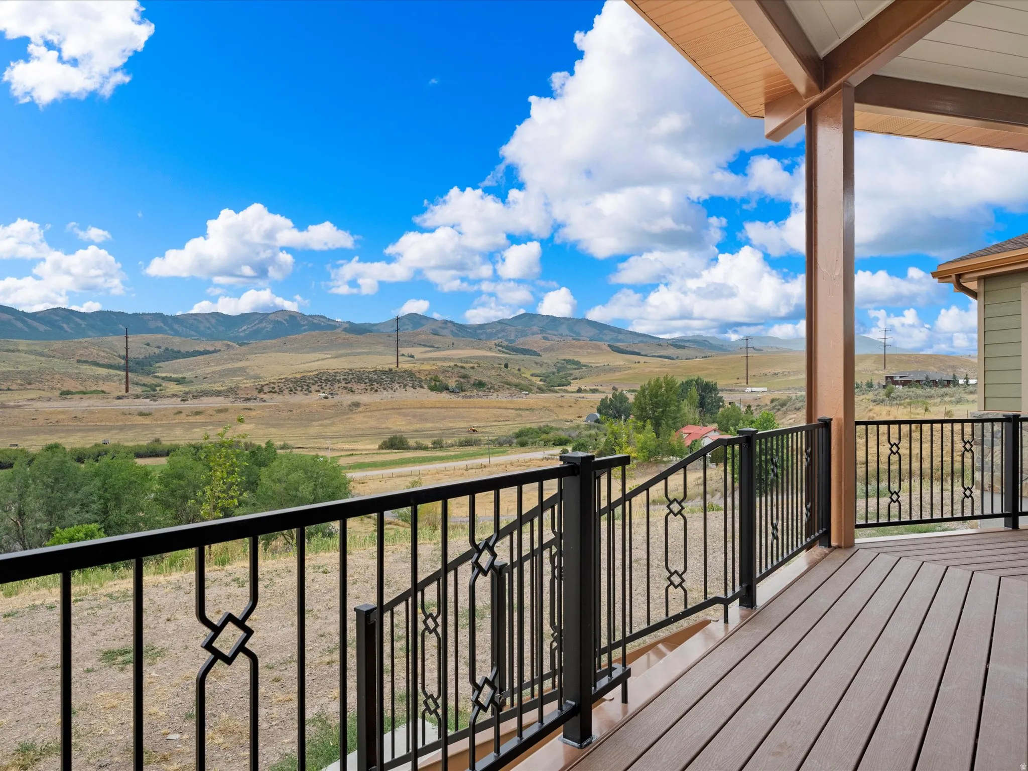 Exterior deck featuring wood-finish composite decking, decorative metal railings, and a wood-paneled ceiling