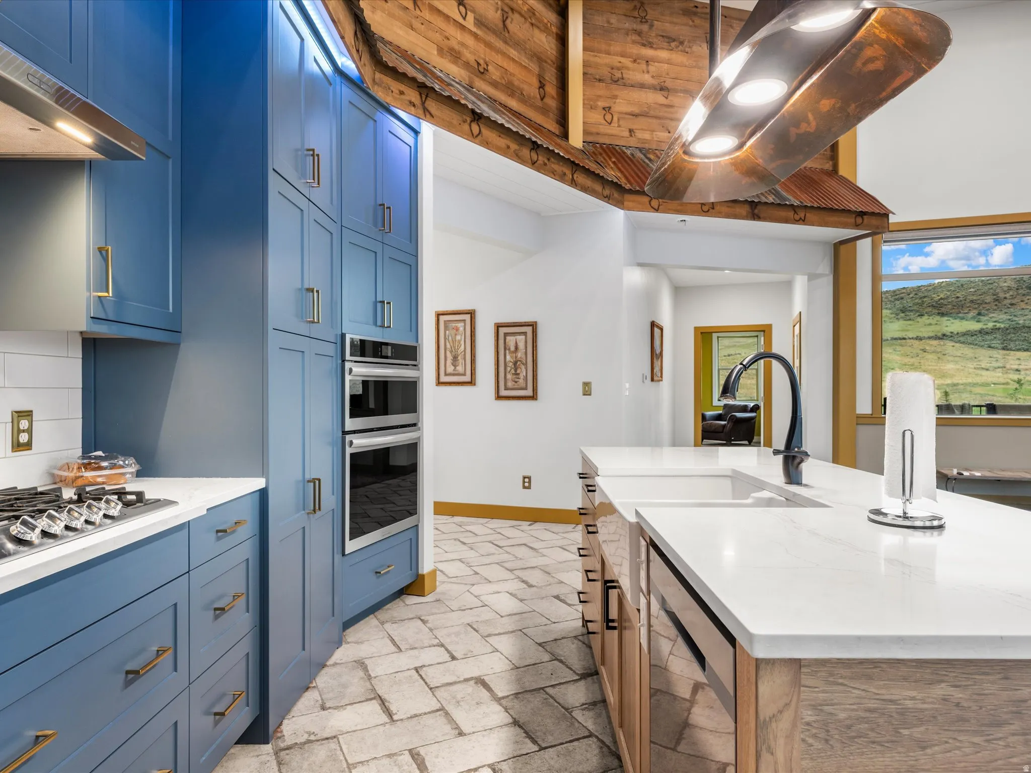 Gourmet kitchen featuring vibrant blue cabinetry, stainless steel double ovens, and a gas cooktop