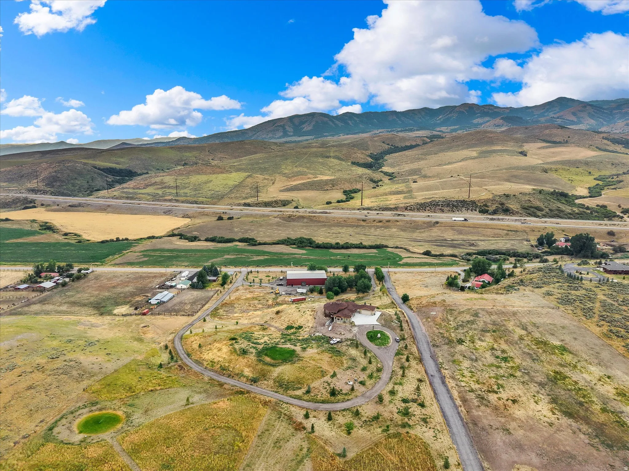 Aerial overview highlighting a sprawling property with multiple structures, including a primary residence with a circular driveway