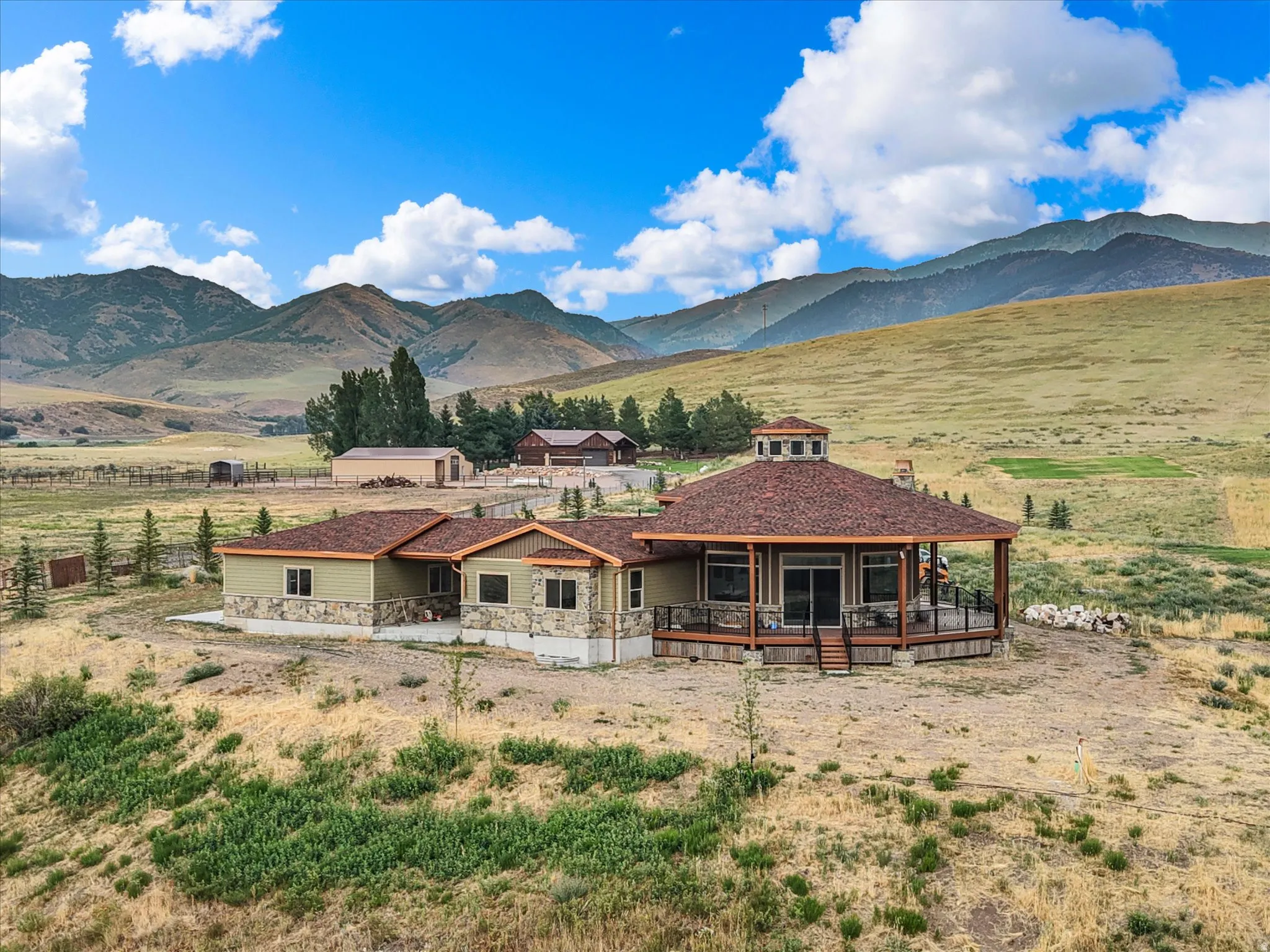 Spacious property featuring a stone and siding exterior, expansive wrap-around deck, and a distinctive turret roofline