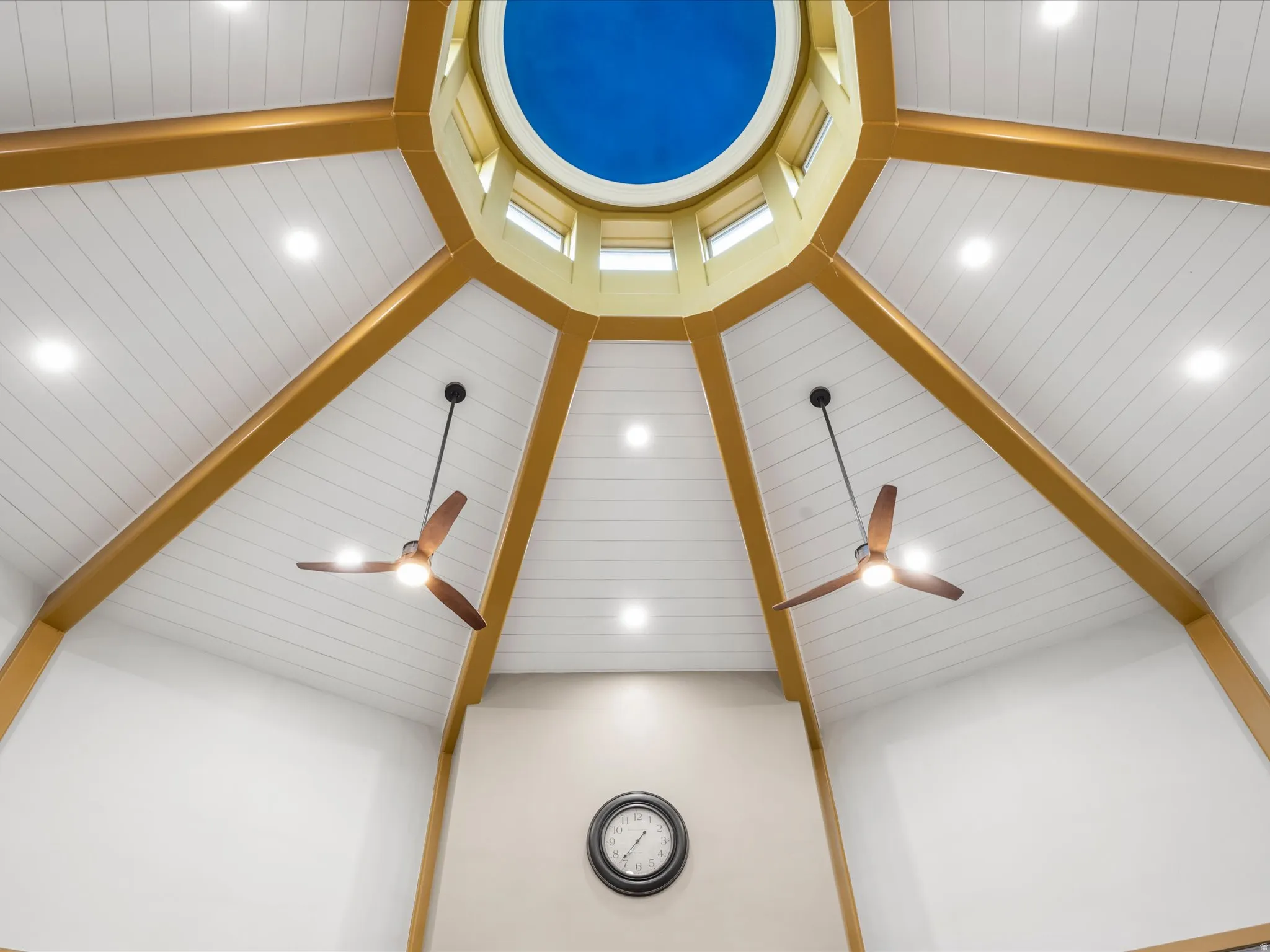 Vaulted ceiling featuring a central domed skylight, exposed wood beams, planked ceiling panels, recessed lighting, and two ceiling fans with integrated lighting