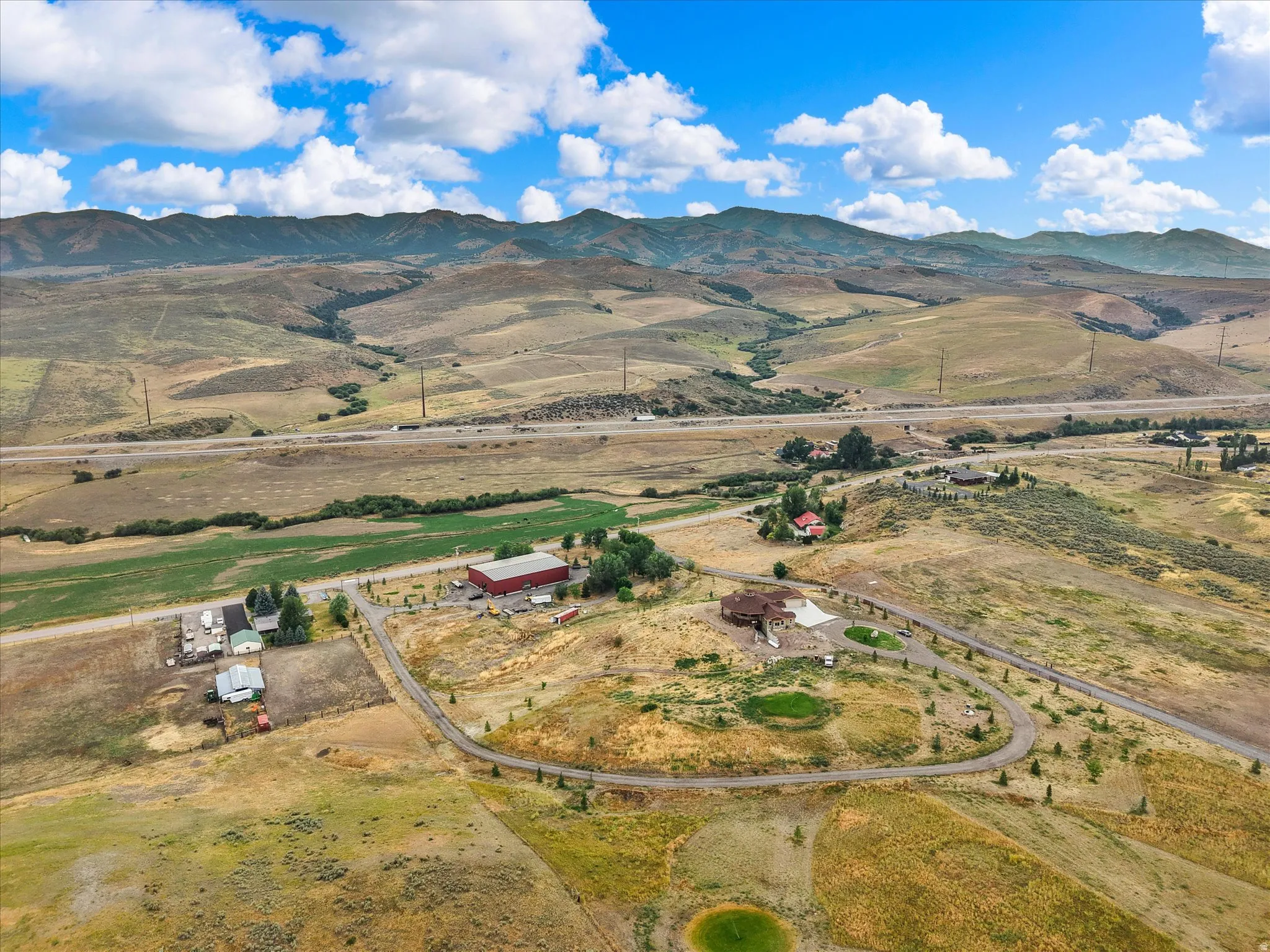 Expansive rural property featuring a large residence, a separate red outbuilding, and a winding private driveway