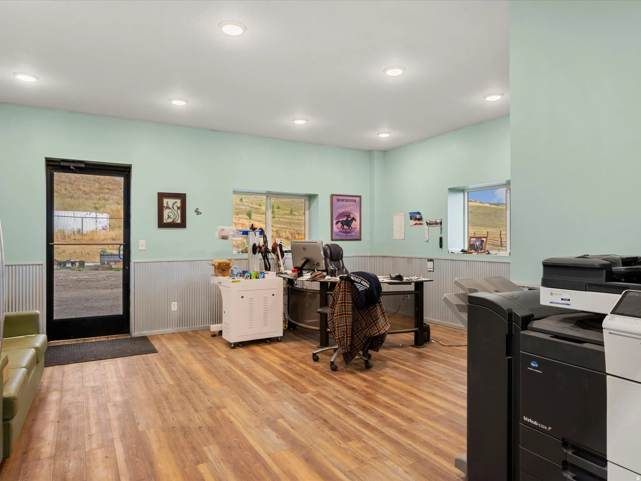 Spacious room featuring wood-finish flooring, recessed ceiling lighting, and a full-light entry door