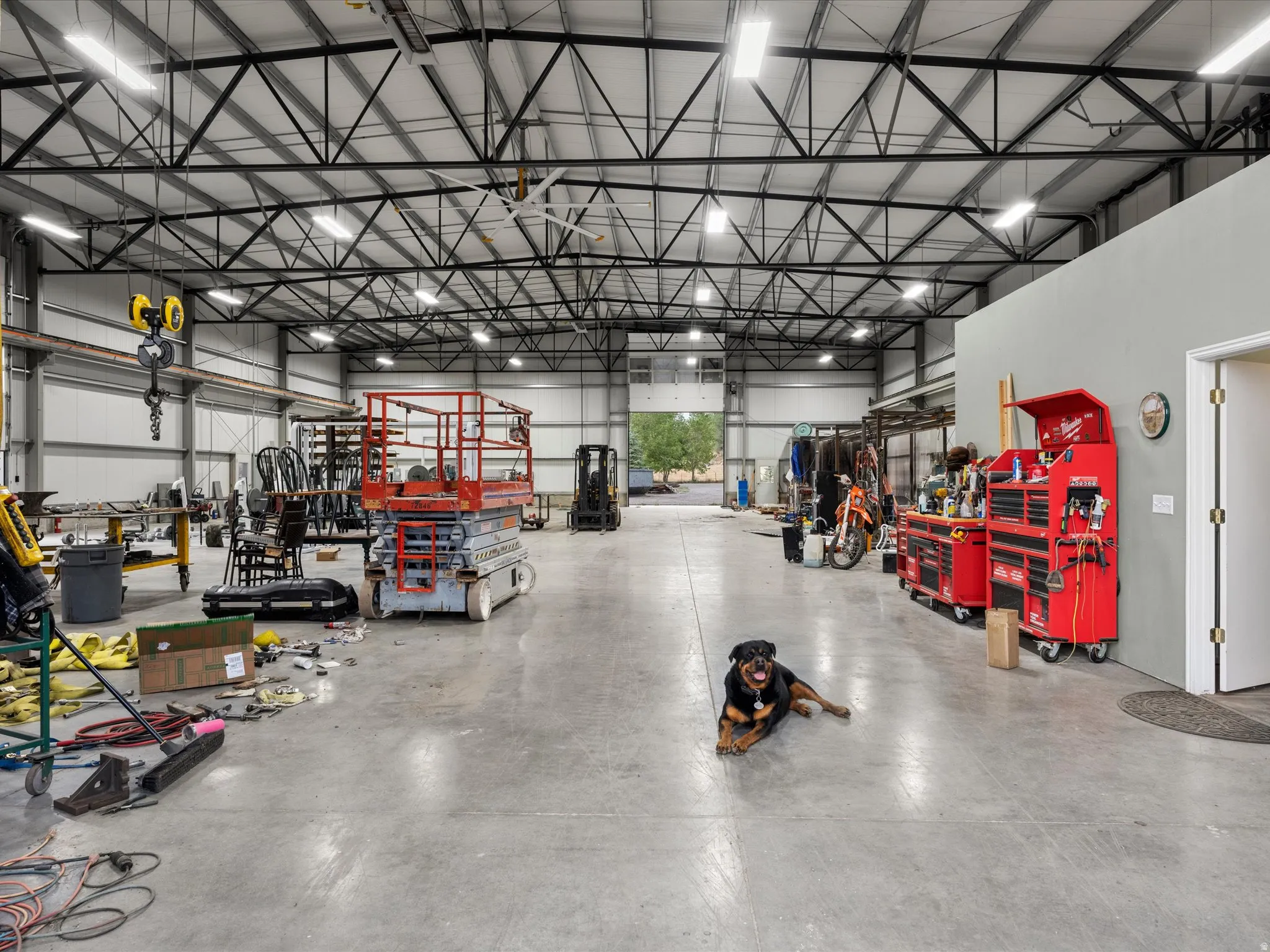 Expansive interior workspace featuring a concrete floor, high ceilings with exposed metal trusses, and overhead lighting