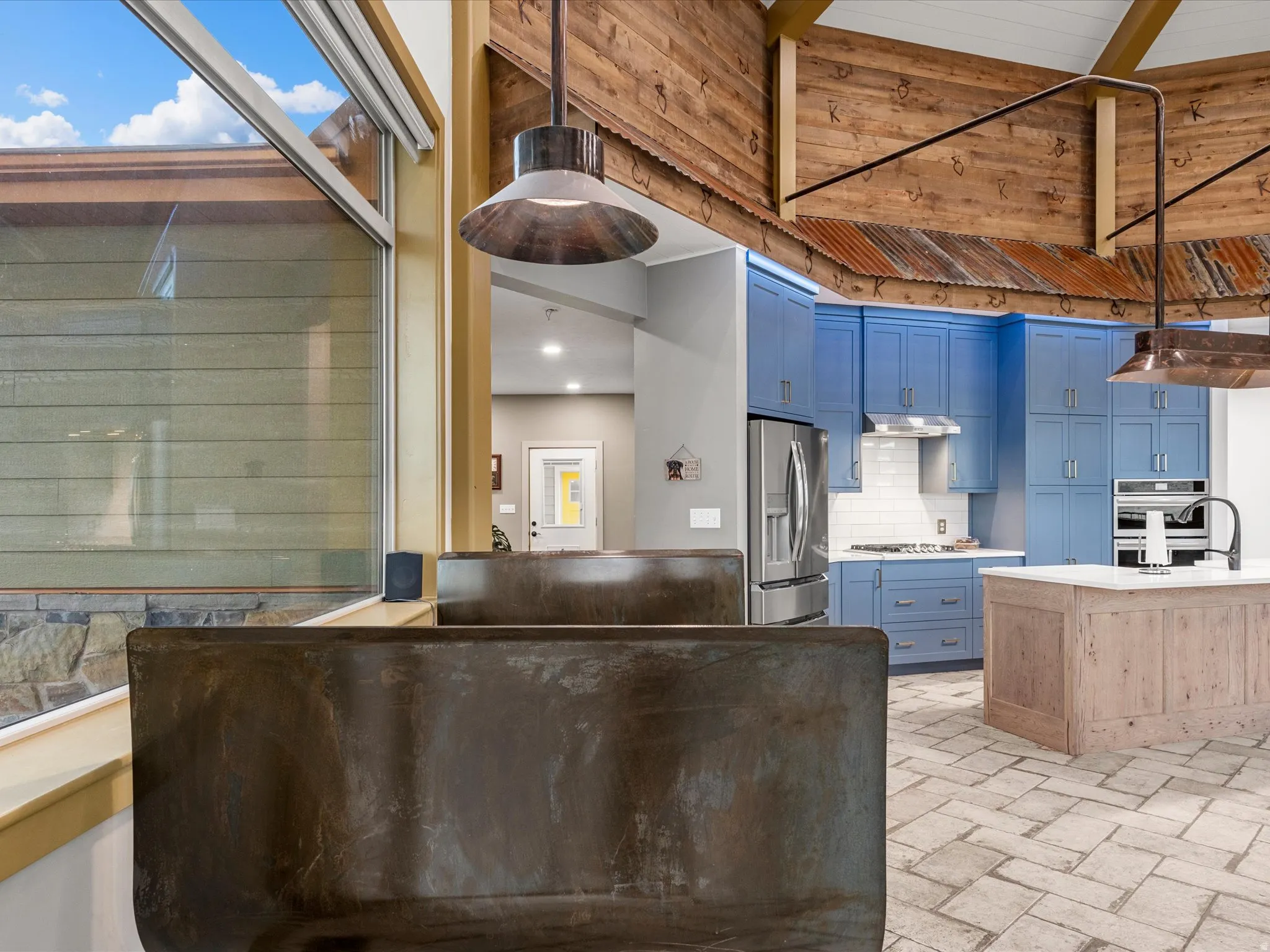 Contemporary kitchen featuring blue cabinetry, stainless steel appliances, a white subway tile backsplash, and a light wood-finish island with a white countertop