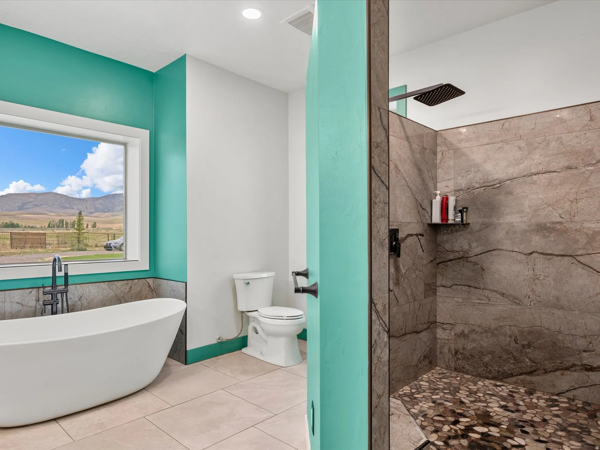 Modern bathroom featuring a freestanding soaking tub with a floor-mounted matte black faucet