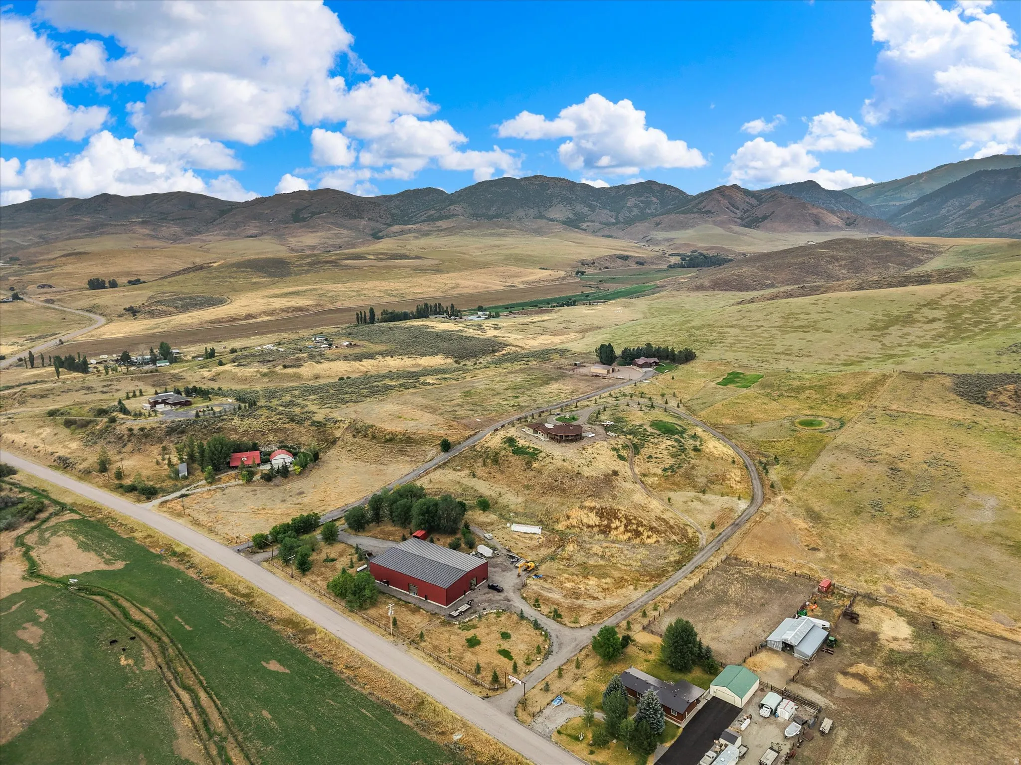 Expansive rural landscape featuring a distant mountain range under a blue sky with clouds