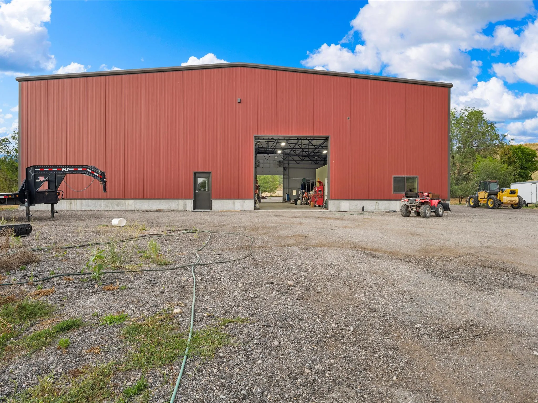 Expansive red metal building with a large roll-up door, a separate pedestrian entry, and a smaller window