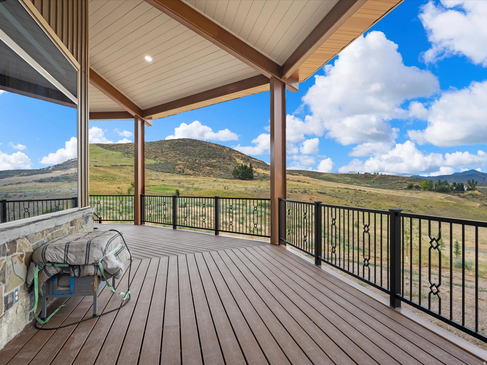 Expansive covered deck featuring composite decking, wood-finish columns, and decorative metal railings