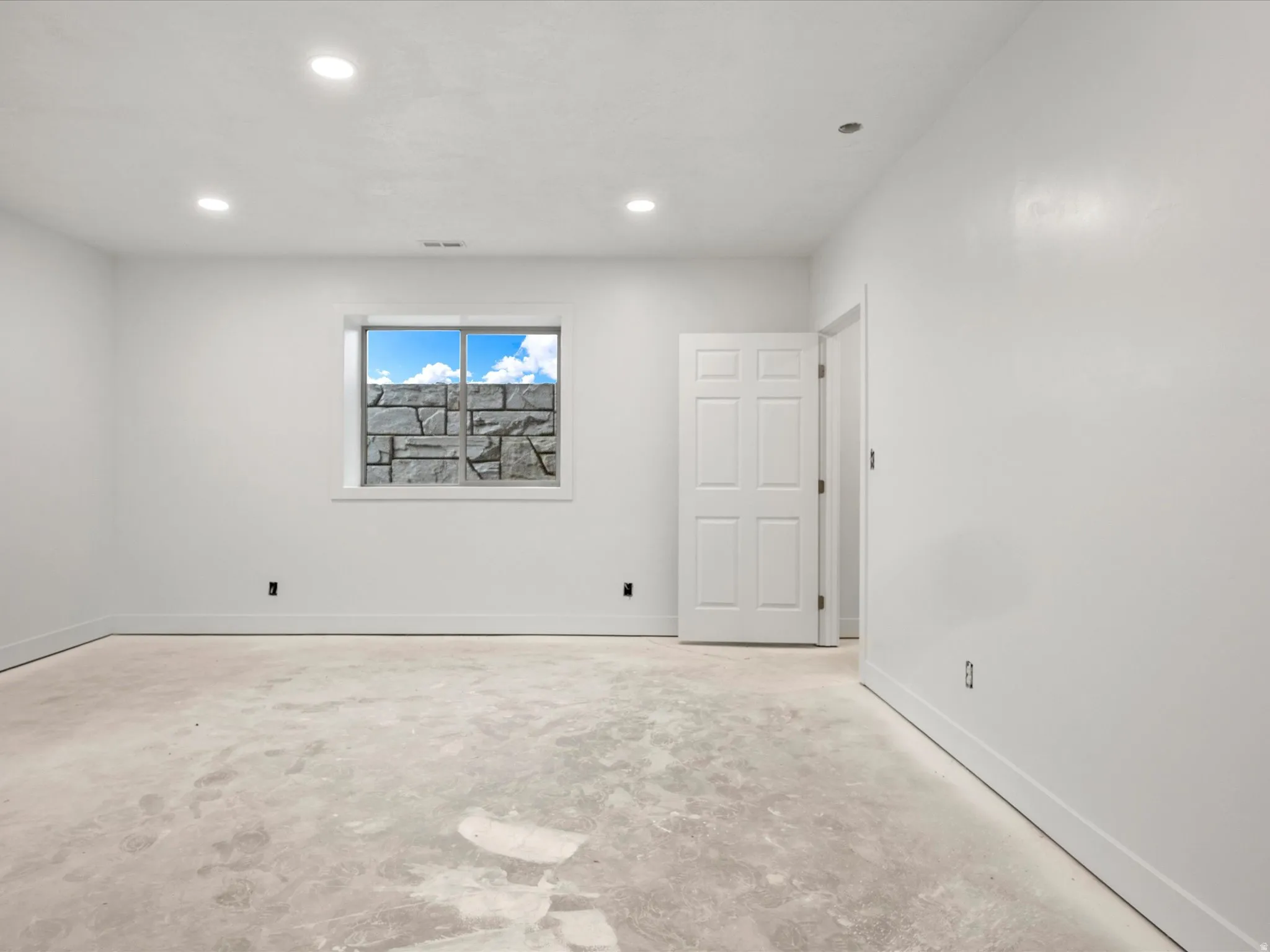Spacious room with a window featuring a stone facade