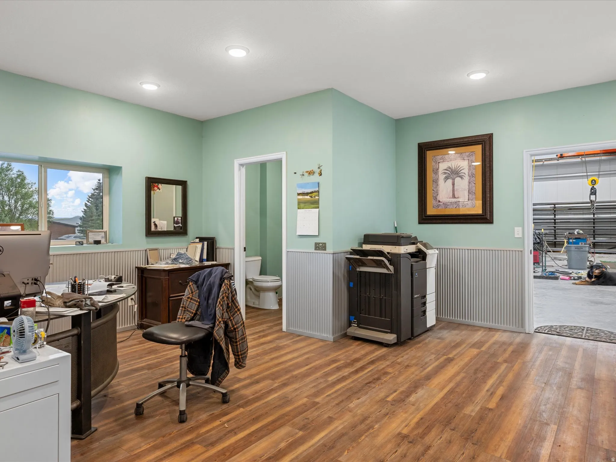 Spacious room featuring wood-finish flooring, recessed lighting, and a light green wall color
