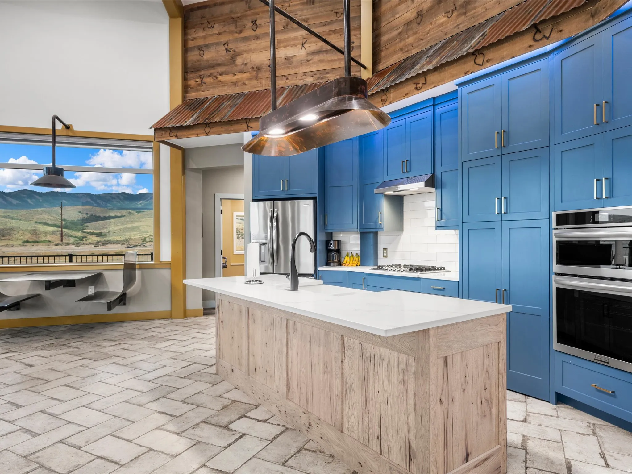 Spacious kitchen featuring a large central island with a light wood finish, white countertop, and integrated sink with a black faucet