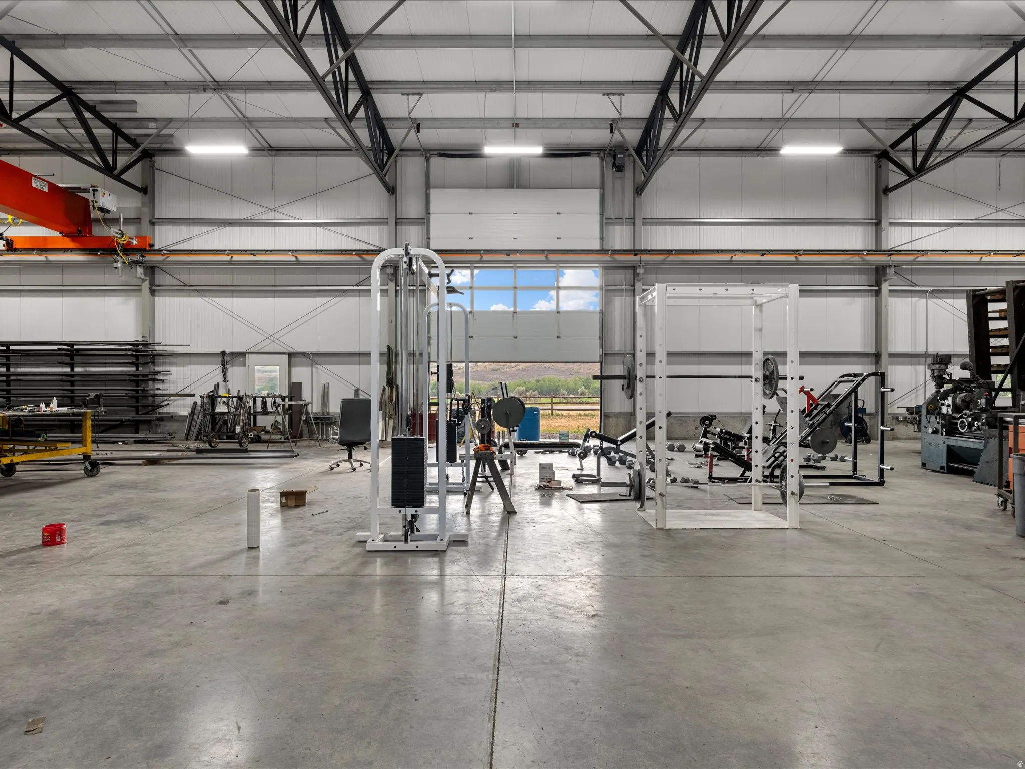 Spacious industrial building featuring high ceilings, exposed metal truss system, concrete flooring, and an overhead crane