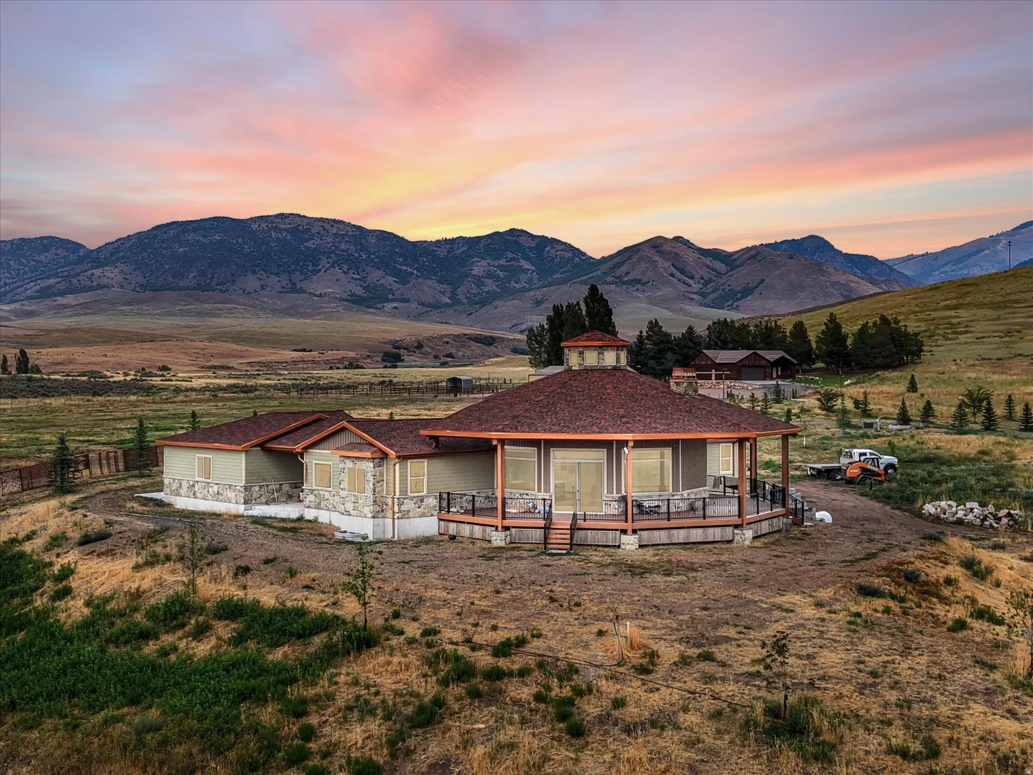 Dome-style residence with a wrap-around deck, stone and siding exterior, and a central cupola