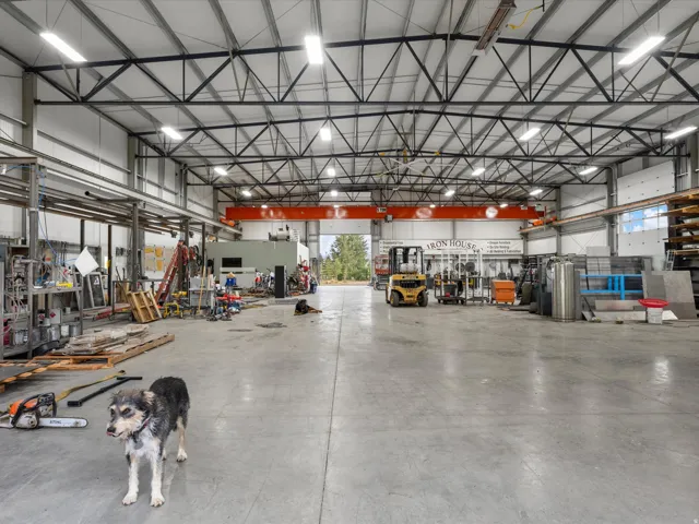 Spacious industrial interior featuring a high-clearance ceiling, concrete flooring, overhead crane system, and multiple roll-up doors