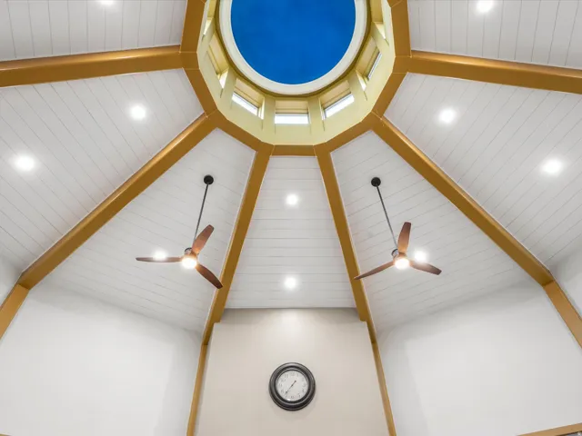 Vaulted ceiling featuring a central domed skylight, exposed wood beams, planked ceiling panels, recessed lighting, and two ceiling fans with integrated lighting