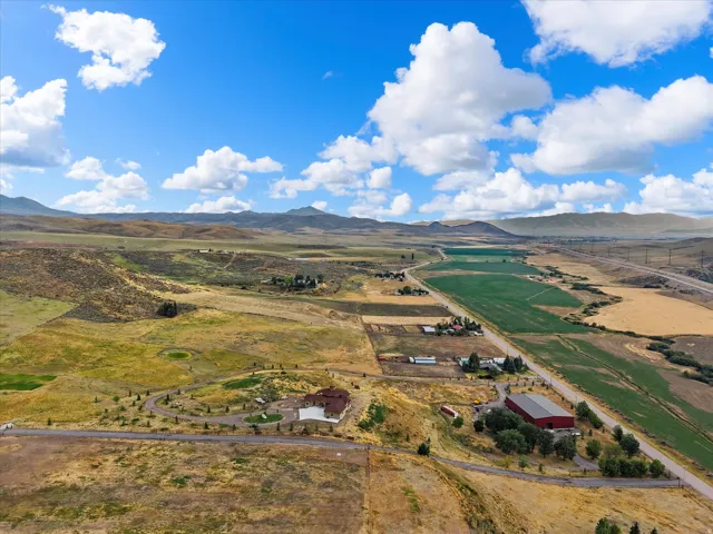 Expansive land parcel featuring a large residence with a circular driveway, a prominent red barn, and multiple agricultural fields