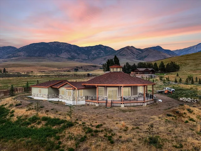 Dome-style residence with a wrap-around deck, stone and siding exterior, and a central cupola