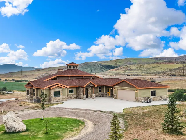 Expansive custom-built residence featuring a stone and siding exterior, a multi-car garage, a distinctive cupola, and a large paved driveway