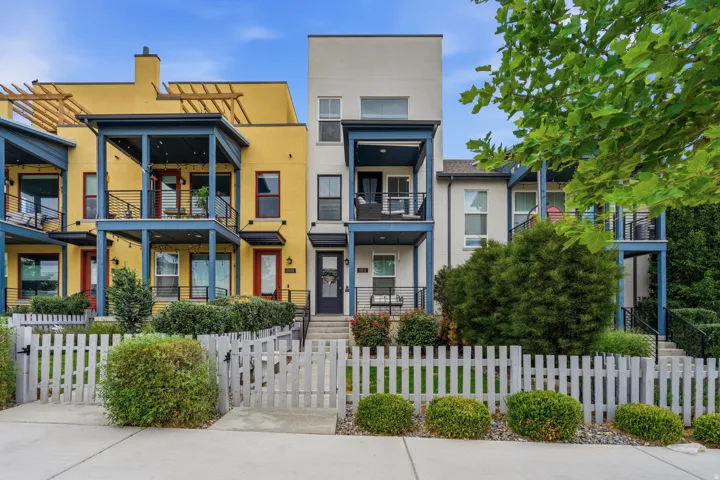 Darling cream townhome with a front porch swing, fully fenced and private yard, and a balcony.