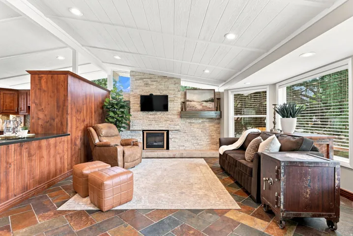 Living area featuring multi-toned slate tile flooring, a stone-clad fireplace with hearth, and recessed lighting