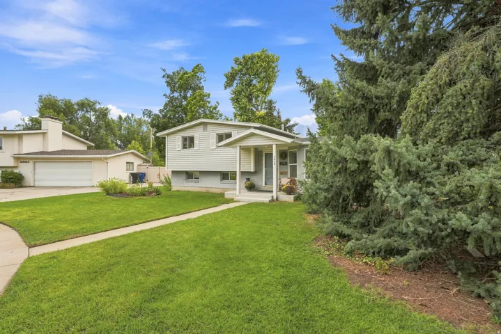 Beautiful residence featuring light-colored siding, a covered front porch with white columns, and a concrete walkway