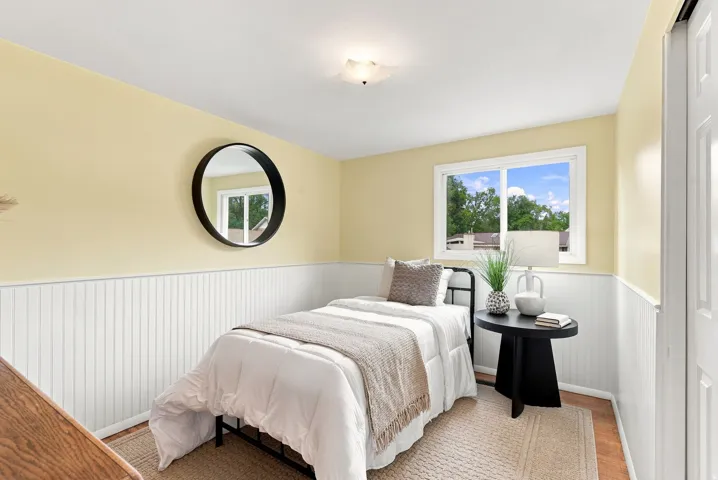 Bedroom featuring board and batten wainscoting, wood-finish flooring, and a single window with white trim