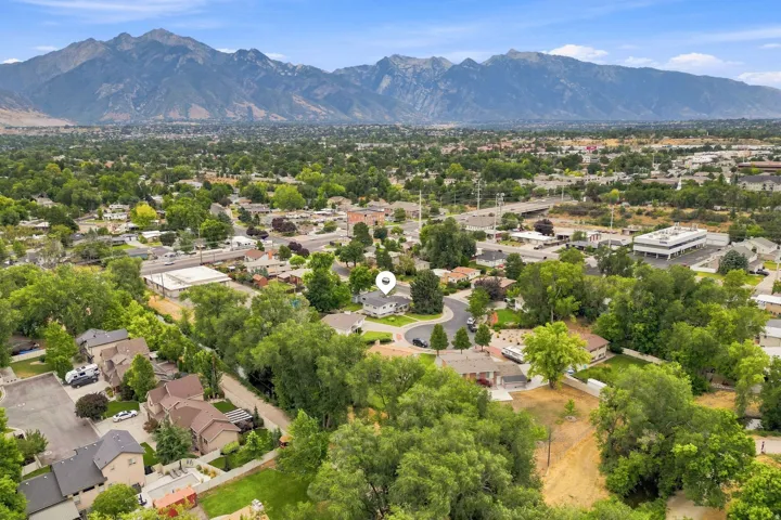 Aerial perspective showcasing a residential area with extensive tree coverage and distant mountains