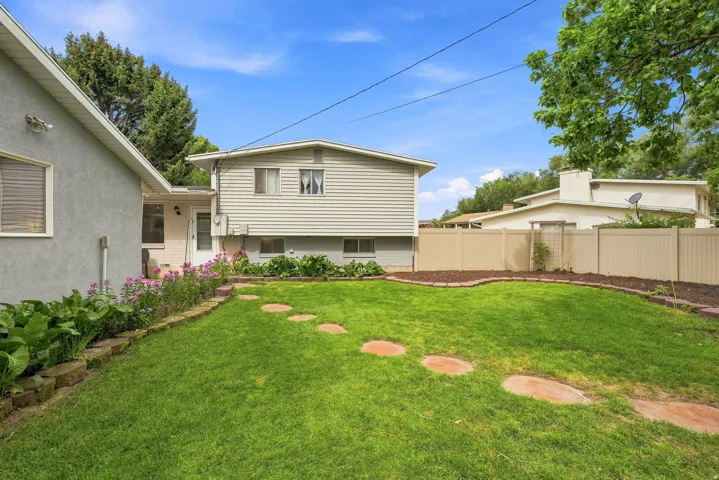 Expansive green lawn with stepping stones leading to a multi-level residence featuring both stucco and horizontal siding finishes