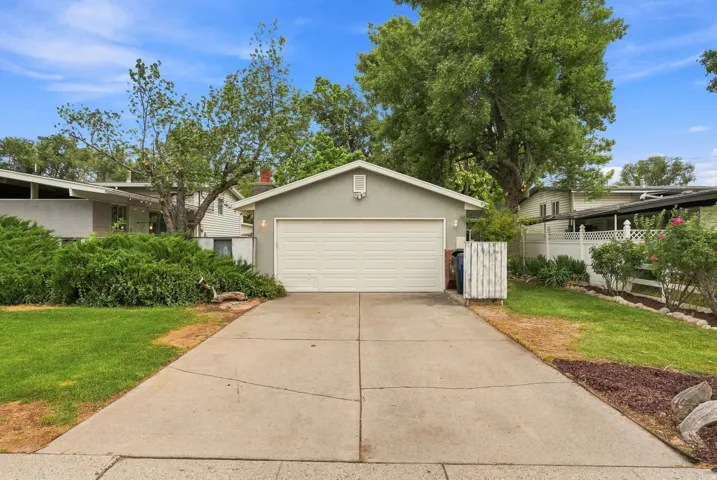 Attached garage with a white sectional door and stucco exterior
