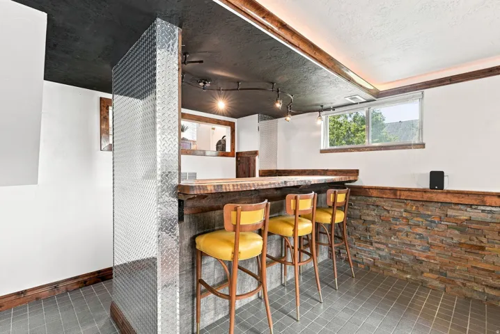 Integrated bar area featuring a wood-finish countertop, stacked stone accent wall, and a diamond plate column