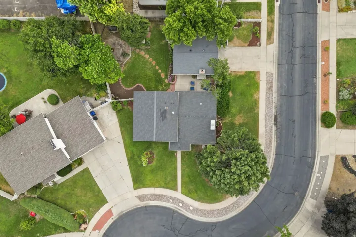 Aerial perspective showcasing a residential property with a dark shingle roof and surrounding green spaces