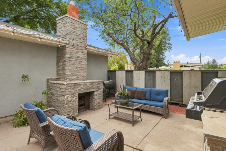 Outdoor patio featuring a stacked stone fireplace with a red brick chimney