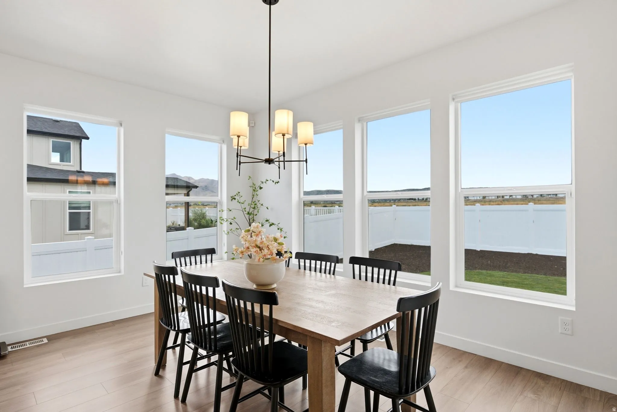 Bright dining area featuring wood-finish flooring, a contemporary chandelier, and multiple large windows
