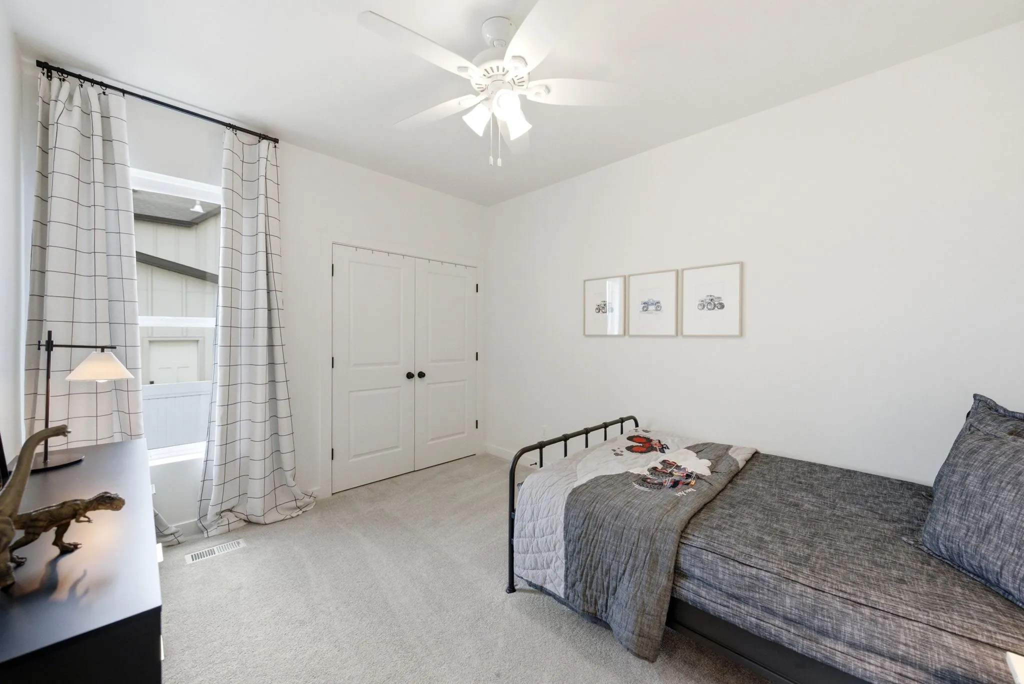 Bright room featuring carpet flooring, a white ceiling fan, and double-door closet