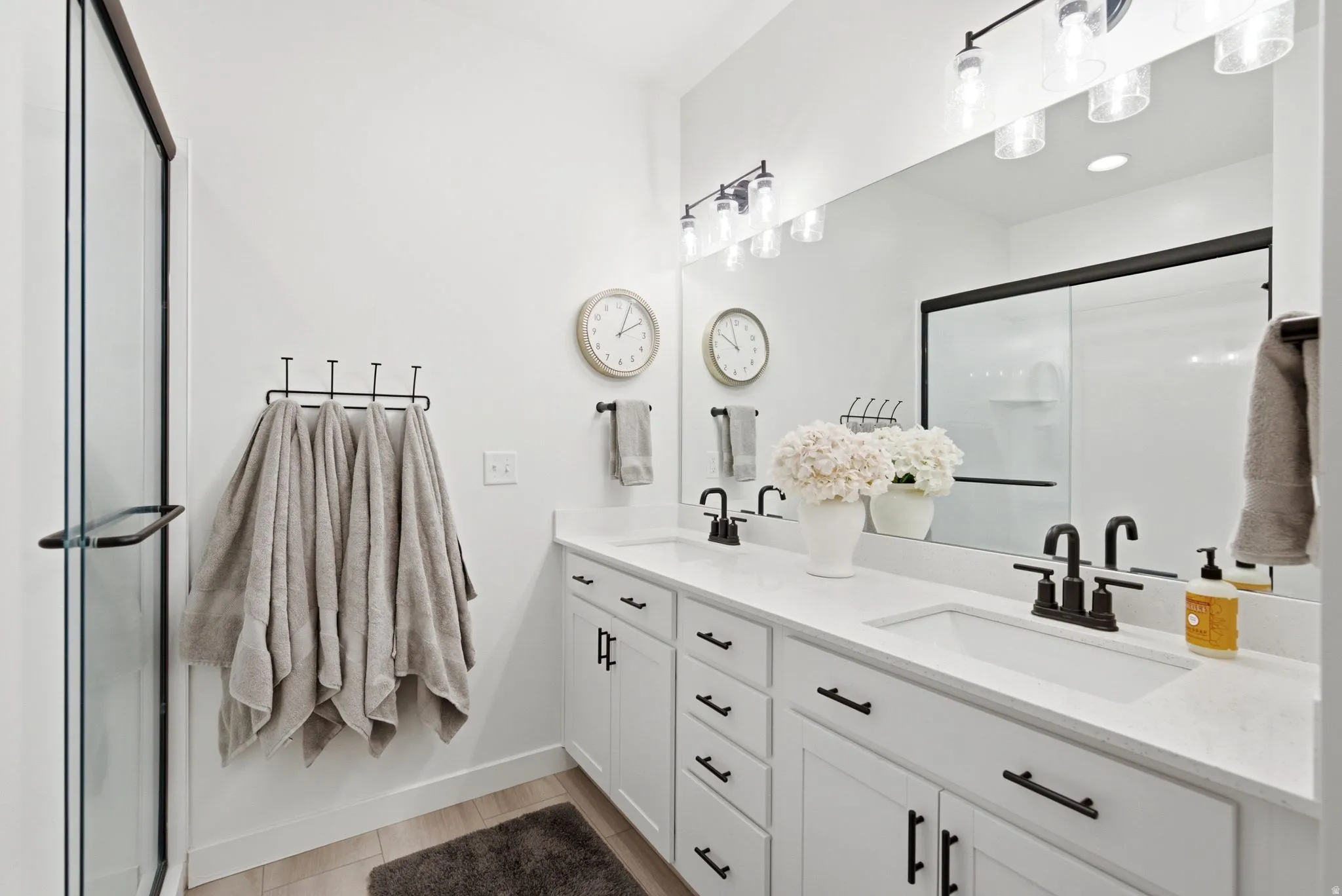 Dual vanity with white cabinetry and countertops, black hardware, and two undermount sinks
