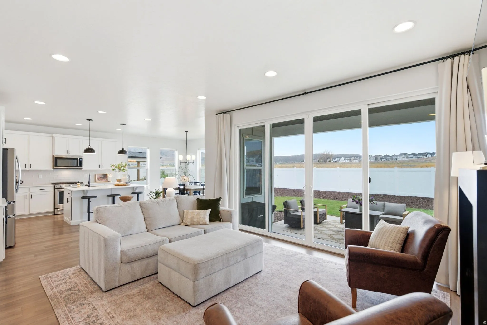 Open-concept living space featuring wood-finish flooring, recessed lighting, and a white kitchen with an island