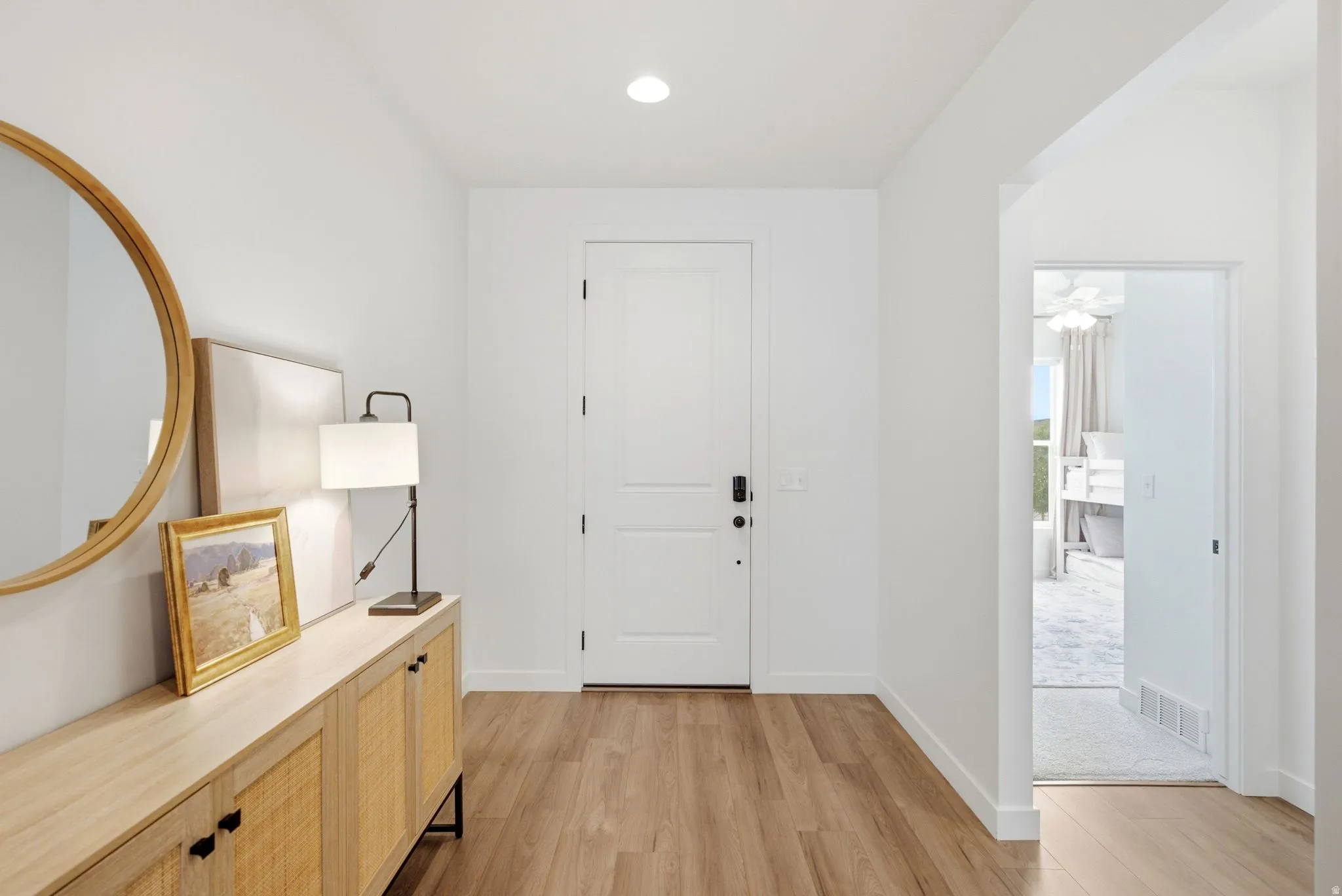 Entryway featuring wood-finish flooring, a white paneled door with contemporary hardware, and recessed lighting