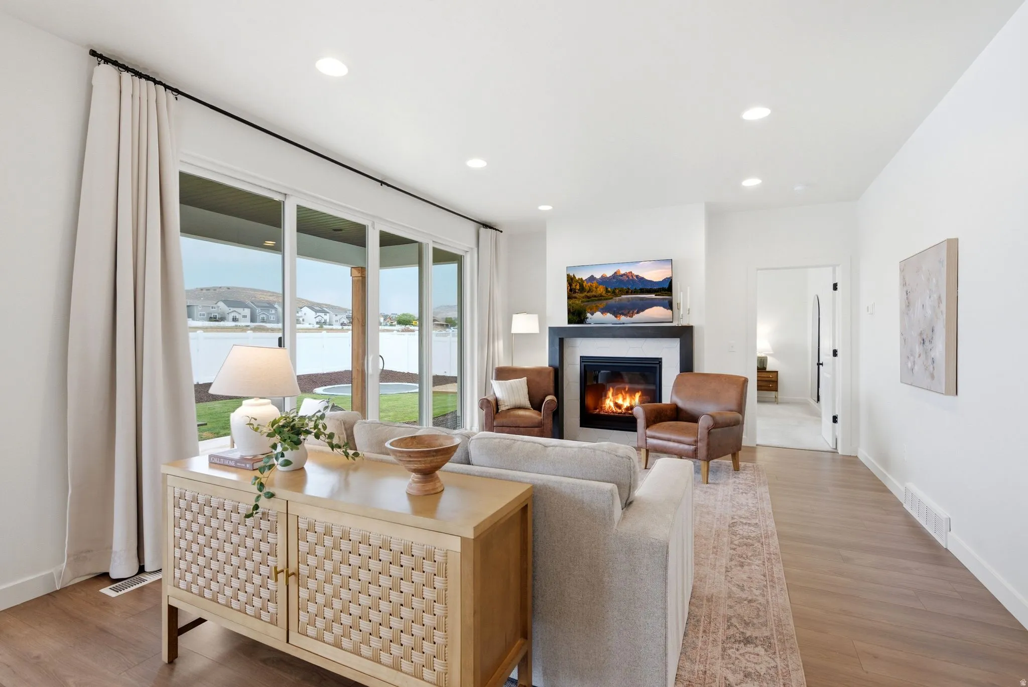 Open-concept living area with wood-finish flooring, a contemporary fireplace, and recessed lighting