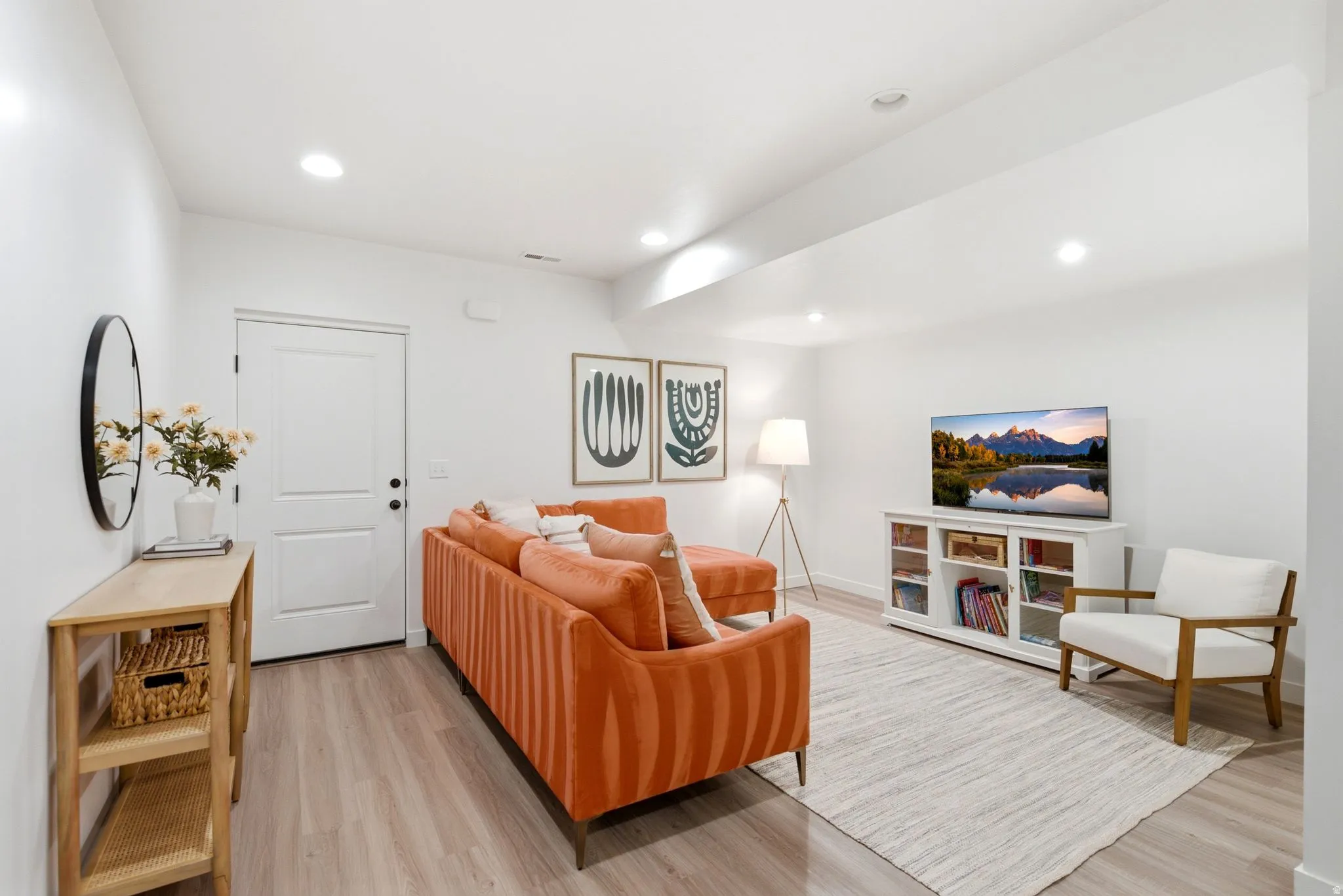 Bright, open living space featuring recessed lighting, a white painted door, and light wood-finish flooring