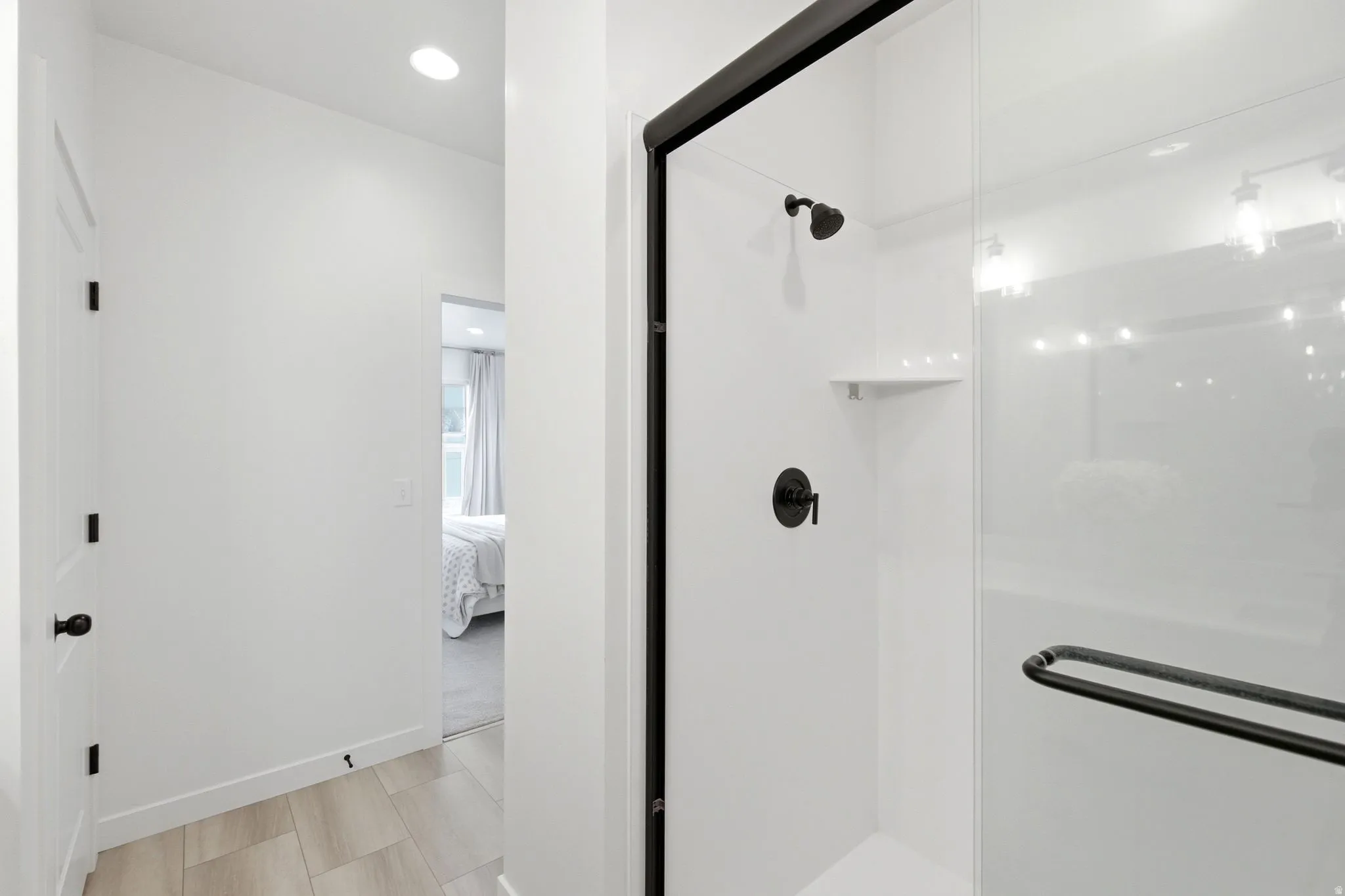 Contemporary shower enclosure featuring matte black hardware, a clear glass panel, and integrated shelving