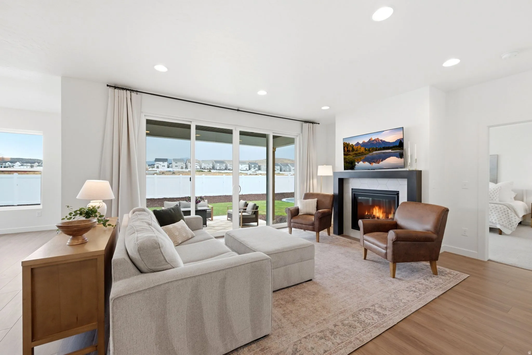 Spacious living area featuring expansive glass sliding doors, a built-in fireplace with a dark mantel, recessed lighting, and wood-finish flooring