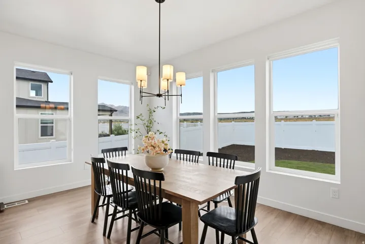 Bright dining area featuring wood-finish flooring, a contemporary chandelier, and multiple large windows