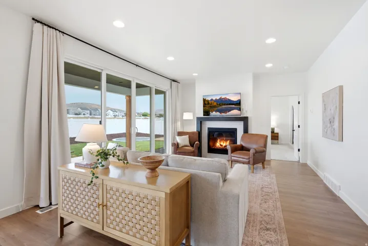 Open-concept living area with wood-finish flooring, a contemporary fireplace, and recessed lighting
