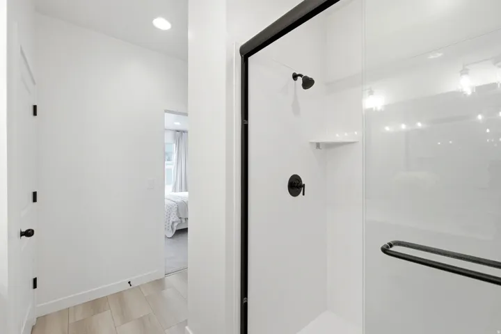 Contemporary shower enclosure featuring matte black hardware, a clear glass panel, and integrated shelving